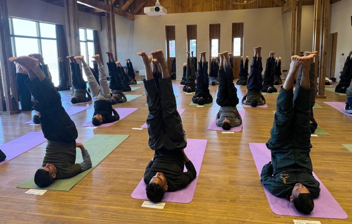 Defence personnel practising a supported inversion in a training hall