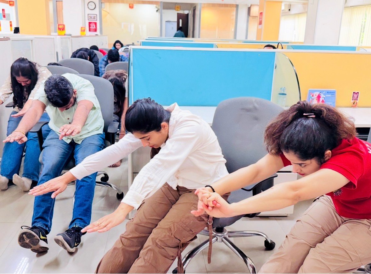 Employees taking part in a seated workplace wellness exercise